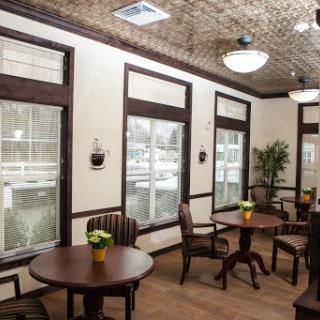 A cozy and inviting waiting area featuring wooden tables and chairs, adorned with small potted plants.