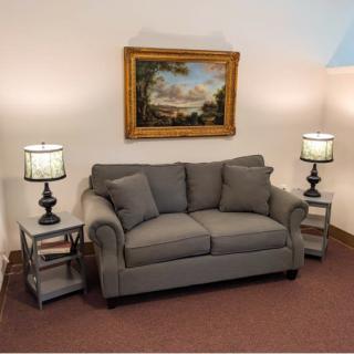 A cozy living room setup with a gray sofa, decorative table lamps, and a landscape painting.
