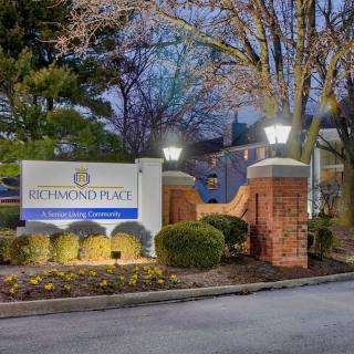 Entrance to an apartment complex with illuminated signage and landscaping at dusk.