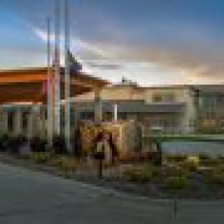 A modern building entrance at sunset with landscaped surroundings and flags.