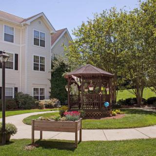A landscaped garden with a gazebo and surrounding greenery next to a residential building.