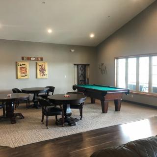 A spacious game room featuring a billiards table and seating area with modern design elements.