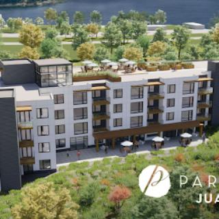 A modern residential building set in a lush landscape.