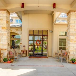 A welcoming building entrance with chairs and potted plants.