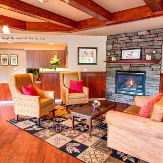 A cozy living room with modern furniture, featuring a fireplace and wooden beams.