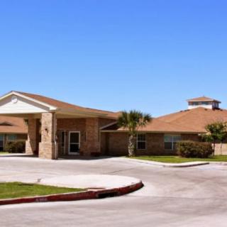 A single-story residential building with a circular driveway on a clear day.