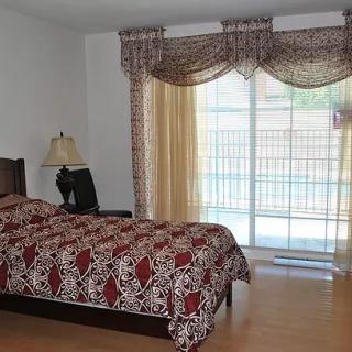 A cozy bedroom with patterned bedspread and elegant curtains.