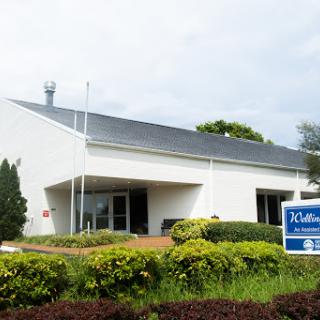 A modern commercial building with landscaped greenery in front.