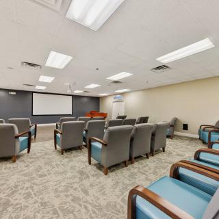 A spacious conference room equipped with comfortable seating and a large projector screen.