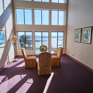 A spacious room with large windows offering a scenic view, featuring a small dining setup.