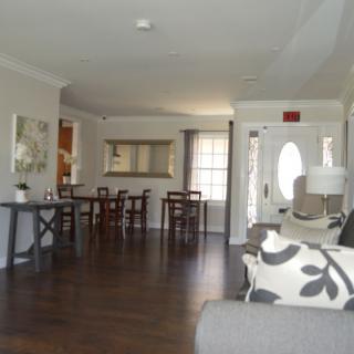 A spacious living room with a view of the dining area, featuring hardwood floors and elegant decor.