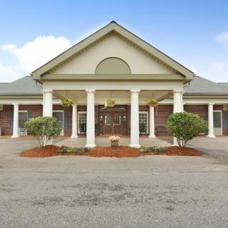A symmetrical building entrance with prominent columns and landscaped surroundings.