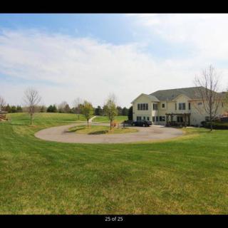 A suburban house with a large lawn and driveway on a clear day.
