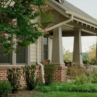 A charming house with a porch surrounded by lush greenery.