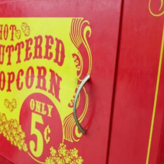 A vintage-style sign advertising hot buttered popcorn for only 5 cents.