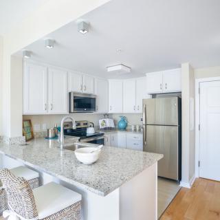 A modern kitchen featuring white cabinets, granite countertops, and stainless steel appliances.