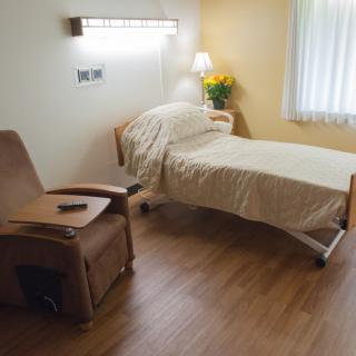 A clean and minimalist hospital room featuring a bed and chair.