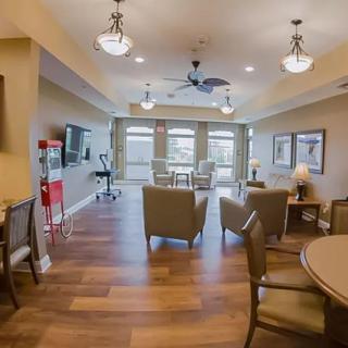 A modern living room with a seating area, wooden floors, and plenty of natural light.