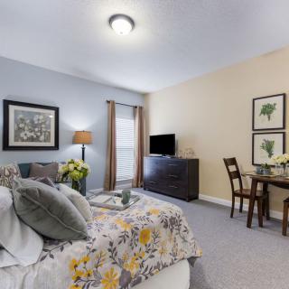 A cozy bedroom with modern decor, featuring a bed, TV, and dining table.