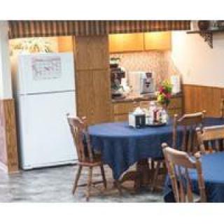 A cozy kitchen-dining area with wooden furniture and blue tablecloths on the tables.