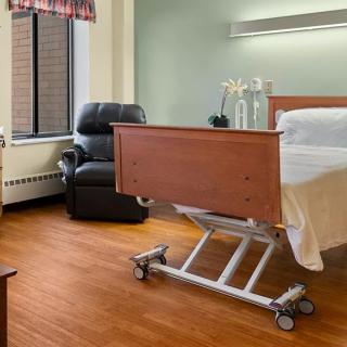 A clean and well-organized hospital room with a patient bed and comfortable seating.