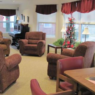 A cozy living room with comfortable chairs, a small Christmas tree, and warm decorations.