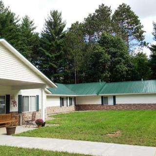 A single-story residential building surrounded by a grassy lawn and trees.