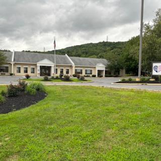 A view of a commercial building set against a cloudy sky, surrounded by lush green grass.