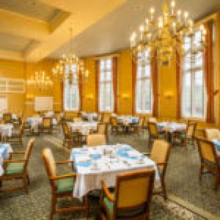 An elegantly decorated dining room with chandeliers and neatly set tables.