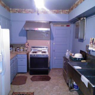 A vintage-style kitchen with blue walls, featuring a stove, sink, and cabinets.