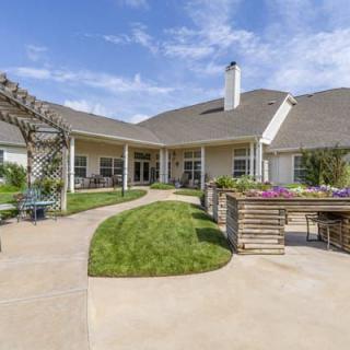A spacious backyard with a well-maintained garden and outdoor seating area under a clear blue sky.