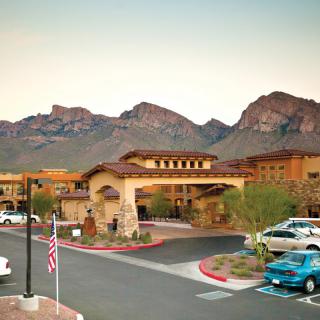 A picturesque resort nestled in a desert landscape with mountains in the background at sunset.
