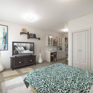 A modern bedroom with stylish decor, featuring a bed with patterned bedding, a television, and a workspace.