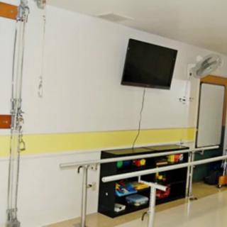 A rehabilitation room equipped with therapy parallel bars and a wall-mounted television.