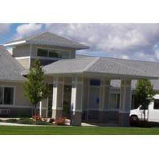 A modern building with a covered entrance and a landscaped front yard.