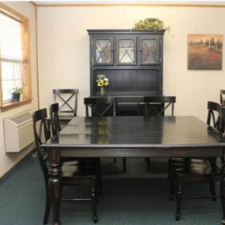 A dining room featuring a dark wooden table set with chairs and a matching cabinet.