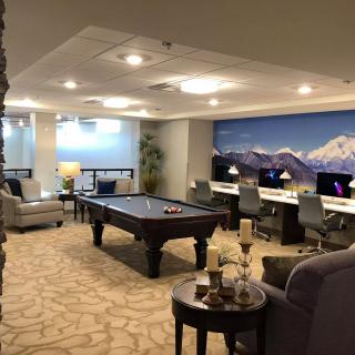 A modern recreation room featuring a pool table, multiple computer workstations, and a comfortable seating area.