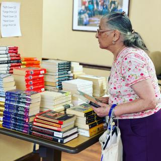 A woman browsing a stack of books in a bookstore.