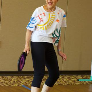 A senior woman engaging in an active exercise session, wearing colorful attire and showcasing joy in movement.