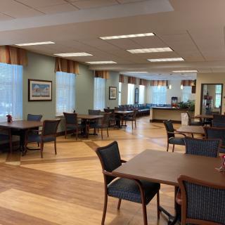A spacious dining area with tables and chairs, featuring ample natural light from the large windows.