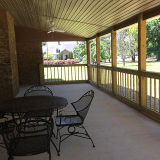 A covered porch with iron furniture overlooking a garden.