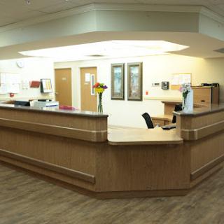 A modern medical reception area with a wooden front desk and welcoming decor.