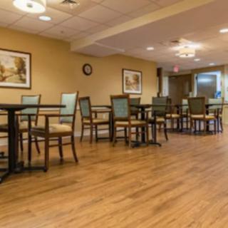 A cozy dining area with wooden flooring and neatly arranged tables and chairs.