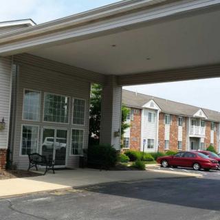 The entrance of a hotel with cars parked in the front.