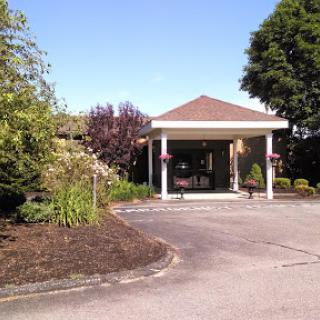 A welcoming entrance to a building surrounded by well-maintained landscaping on a sunny day.