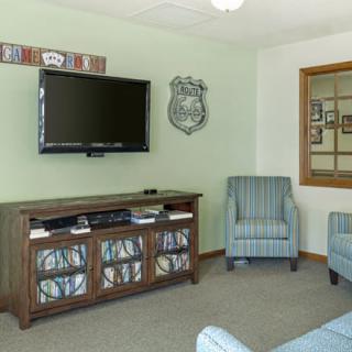 A cozy living room featuring a wall-mounted television, an entertainment center, and comfortable armchairs.