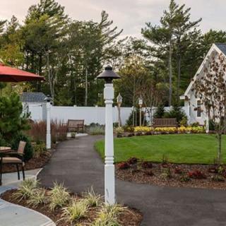 A beautifully landscaped garden with a paved pathway, lush green lawn, and decorative lamp posts.