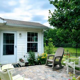 A cozy backyard patio with outdoor seating and lush greenery surrounding a small house.