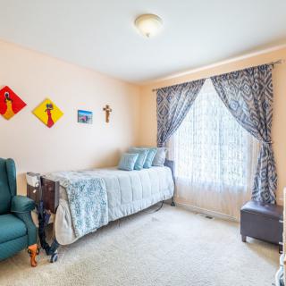 A cozy bedroom with a twin bed, armchair, and decorative wall art.