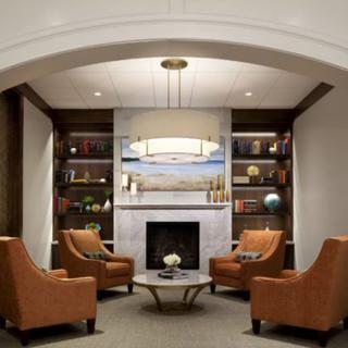 A modern living room with a cozy seating area around a fireplace, featuring armchairs and built-in bookshelves.